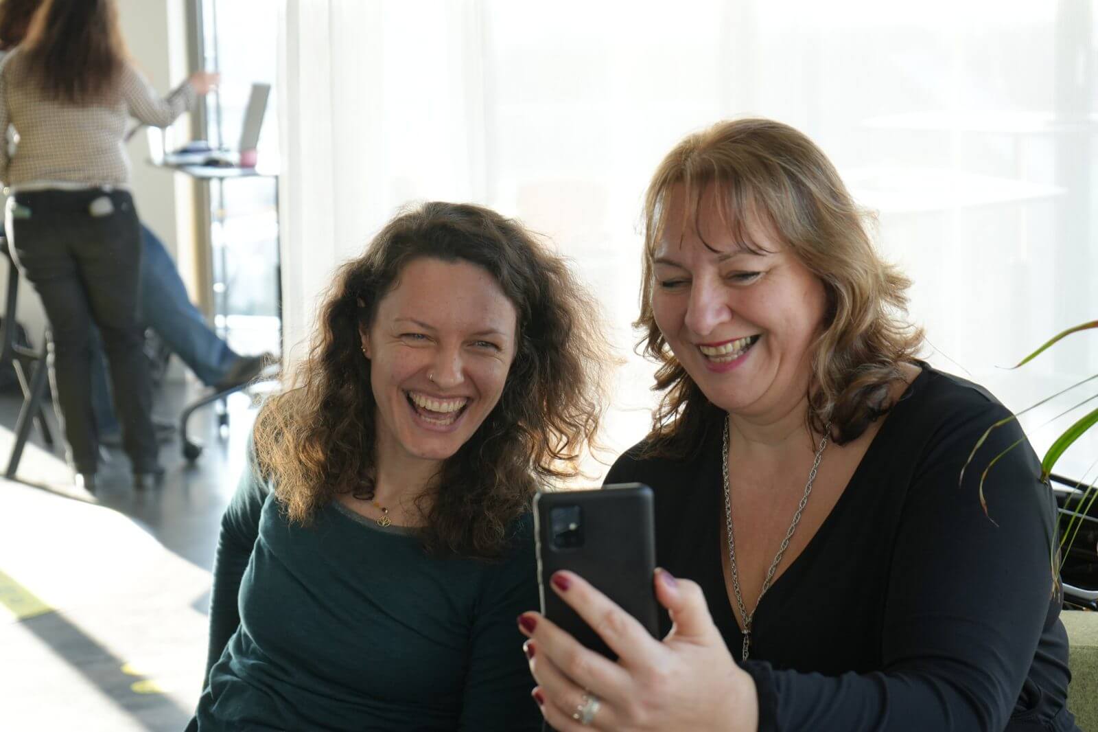 Zwei Teilnehmerinnen lachen über ein Ergebnis am Handy